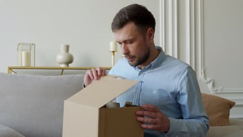 Man opening package at home on couch