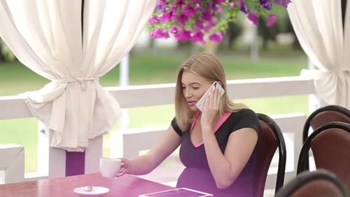 Smiling girl spending time in a street cafe using digital tablet