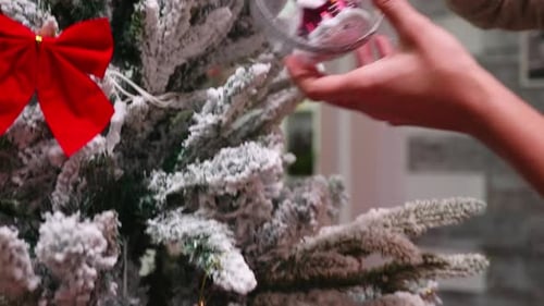 Woman Decorates Christmas Tree with Ornaments