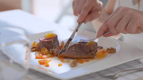 Rotes Fleisch auf einem Teller schneiden.