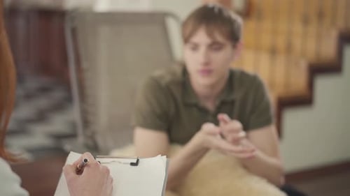 Junger Mann sitzt im Büro des Psychologen und erzählt ihr von seinen Problemen
