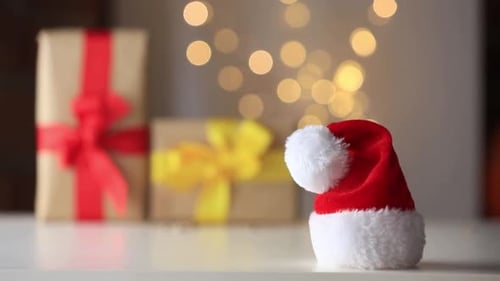 Little Santa Claus hat on a table with gifts on background