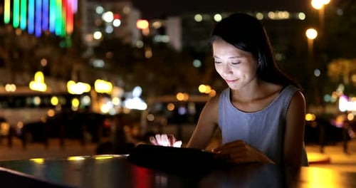 Woman Using Tablet at Night in City