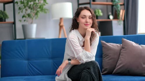 Smiling Woman Sitting on a Blue Couch Indoors