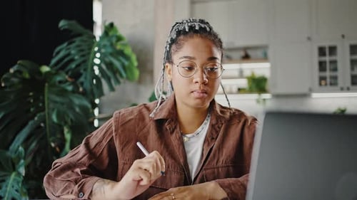 Woman Works on Laptop and Writes in Notebook