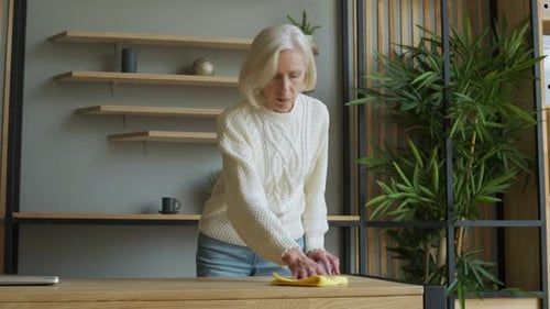 Woman Cleans Wooden Desk with Cloth at Home