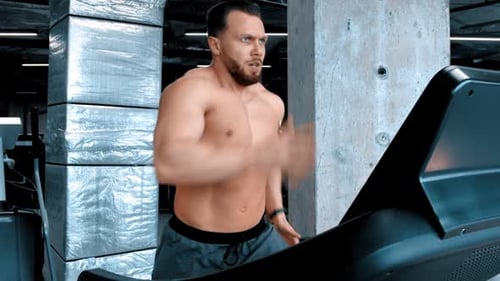 Shirtless Muscular Man Runs on Treadmill in Gym