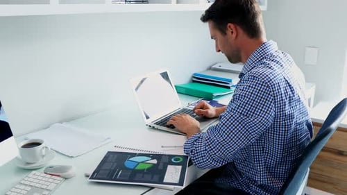 Man Works From Home Using Laptop and Tablet