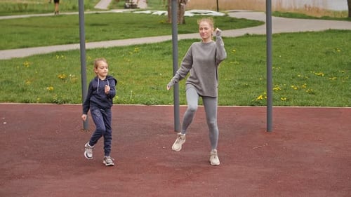 Slow Motion Mother and Daughter Doing Exercises on Open Air Sport Playground. Sportive Family
