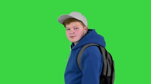 Handsome School Boy Walking By While Listening To Music on a Green Screen Chroma Key