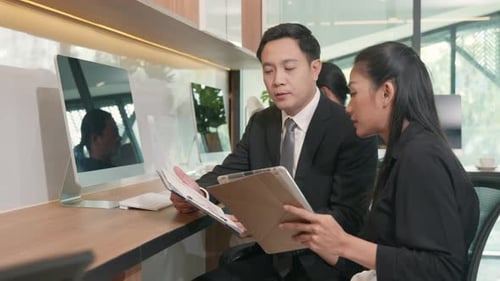 Business Colleagues Reviewing Documents and Tablet at Desk