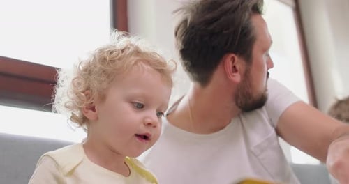 Dad Reads Book with Curly Haired Child Indoors