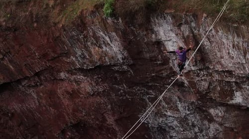 A Man Is Walking on a Tightrope Over a Massive Pit Aerial View