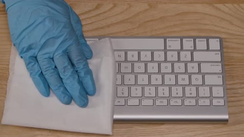 Hands in Gloves Cleaning and Typing on Keyboard
