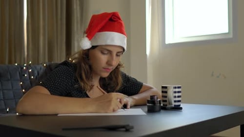 Close Up Shot of Young Woman in a Christmas Hat Calligraphy Writing on a Paper Using Lettering