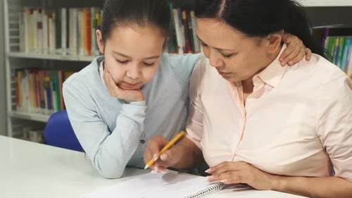 Mother Helps Child with Homework in Library