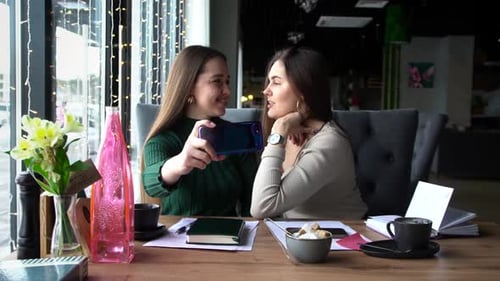 Women Smiling Taking Smartphone Selfies in Cafe