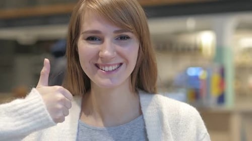 Thumbs Up By Young Woman in Cafe