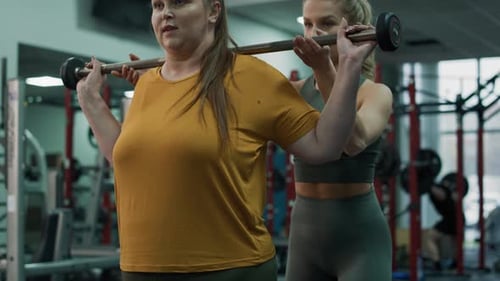 Caucasian woman with overweight doing training with fitness instructor at the gym. Shot with RED hel