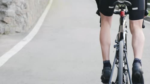 Cyclist Rides Bike on Paved Road in City