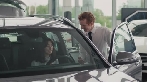 Salesman Talking to Woman Choosing Car in Dealership