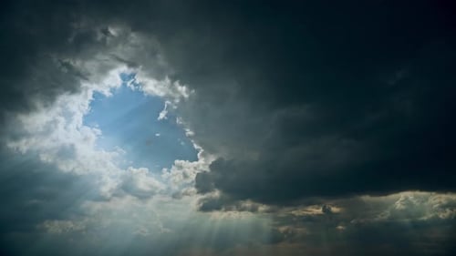 Sun Rays Shining Through Dark Storm Cloudy Rainy Sky With Fluffy Rain Clouds