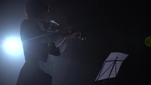 Silhouette of Musician Playing Violin in the Dark