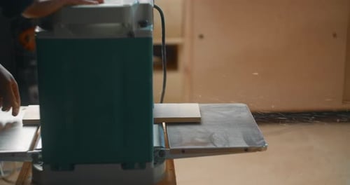 Carpenter Uses Electric Planing Machine at His Woodworking Workshop Timber Shavings and Sawdust Fall