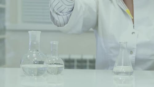 Scientist Transfers Liquid Between Beakers in Lab