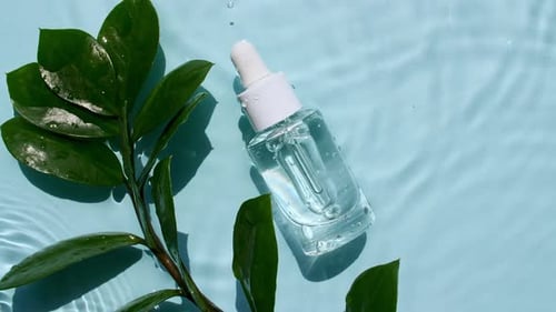 Cosmetic Bottle on Watery Surface with Plant