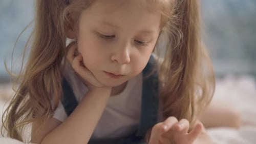 Little Girl Using Smartphone Lying on Bed
