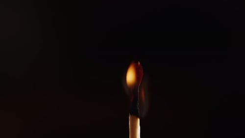 Burning Matchstick Flame Against Black Background