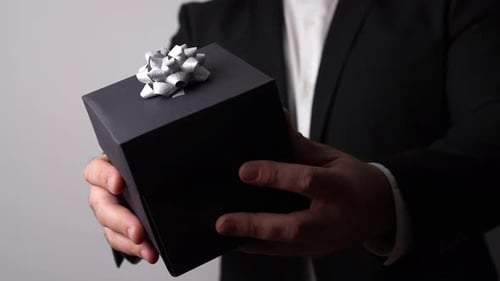 Man Holds Black Gift Box with Silver Bow