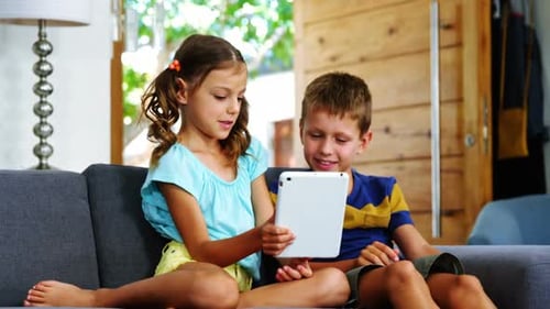 Children Using Tablet on Sofa Together