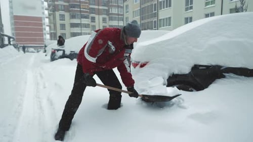Man shovels snow away from car in winter