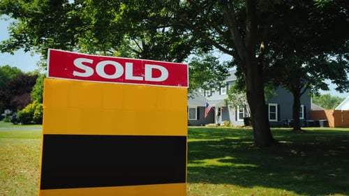 A Plate with the Words Sold, in the Background a Typical American House with the Usa Flag