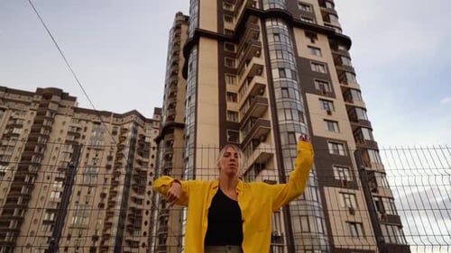 Stylish Woman Dancing in Front of City Buildings