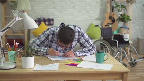 Young Man Drawing at Table in Bright Room