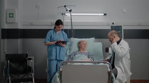 Doctor Consulting Sick Patient with Stethoscope in Hospital Ward