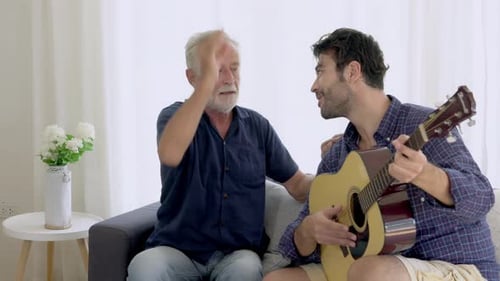 Young Man Plays Guitar for an Adult Man