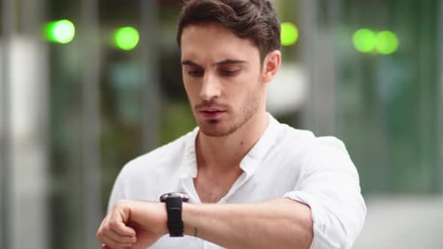 Man Uses Smartwatch in Urban Environment