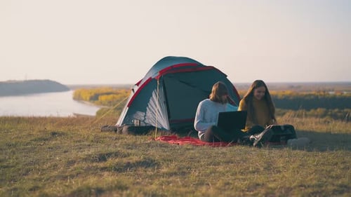 Young Women Camping with Laptop on Hillside
