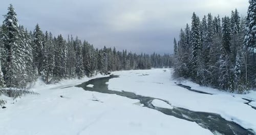 Stream flowing through snowy forest 4k