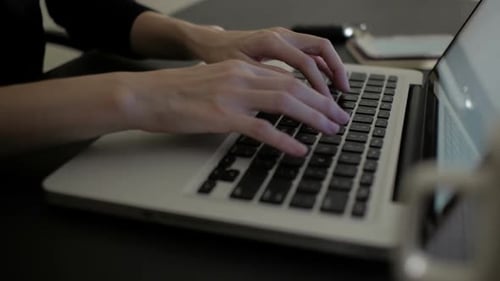 Hands Typing on Laptop Keyboard in Office