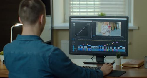 Male Video Editor Works with Footage and Sound on His Personal Computer. His Office Is Modern and