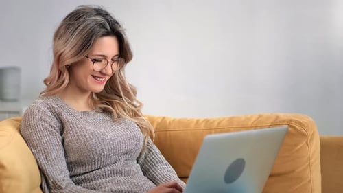 Woman Working on Laptop While Sitting on Sofa