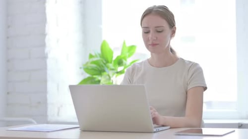 Woman Uses Laptop and Smiles in Bright Office
