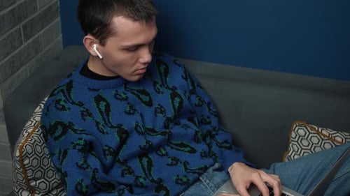 Young Adult Works on Laptop on Couch
