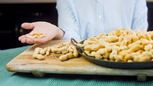 Handful of Peanuts Above Bowl on Tray