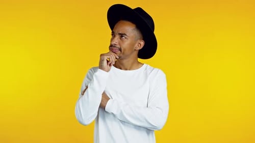 Stylish Man Thinking in Front of Yellow Background